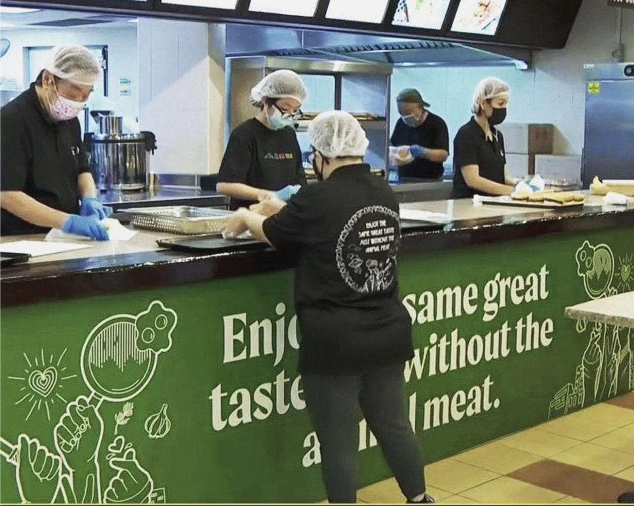 The Social Kitchen team preparing food together behind a kitchen counter